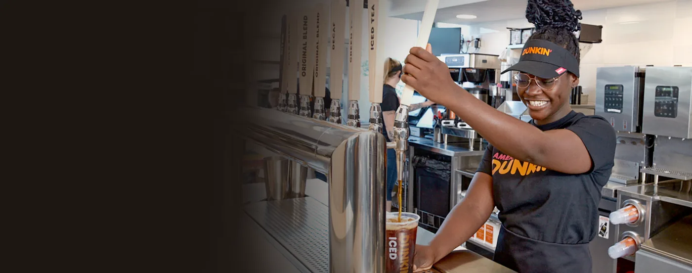 A PPP Donuts Network crew member pouring cold brew at the tap wall behind the counter