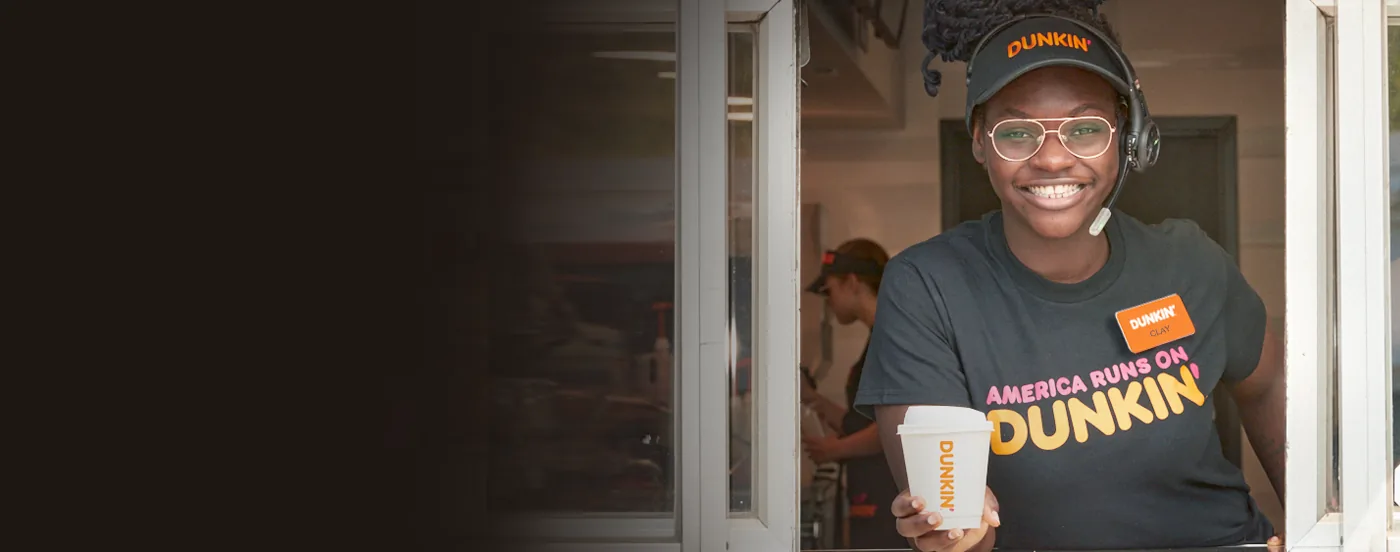A PPP Donuts Network crew member handing an order through the drive-thru window